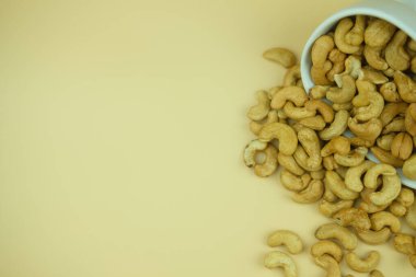 Roasted cashew nuts on a yellow background.
