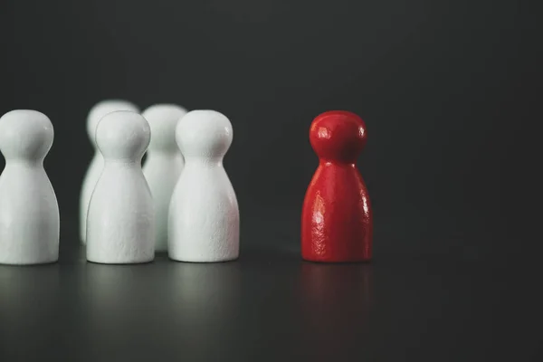 One red wooden figurine standing in front of a group of others for the concepts of leadership and business. Different people. Run to new opportunities. Talent management.