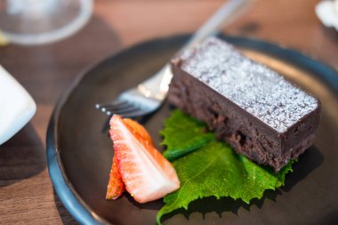 Macro close up of appetizing chocolate brownie with slice of strawberry. Selective focus