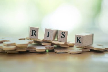 The text on wooden blocks RISK placed on wood jigsaw. Concept of problem solving and investment risk analysis.