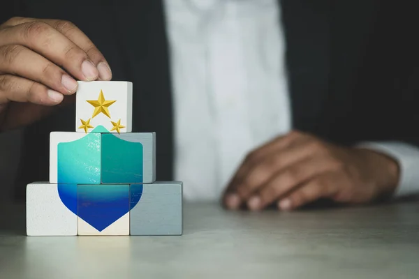 Hand touch white wood cube block on top pyramid with icon shield and stars. The concept of technology internet cyber security and anti virus online