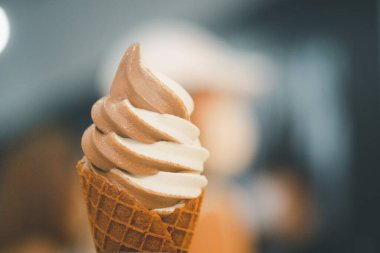 Hand holding a two tone chocolate and vanilla ice cream waffle. Close up