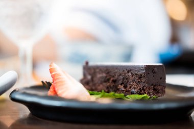 Macro close up of appetizing chocolate brownie with slice of strawberry. Selective focus