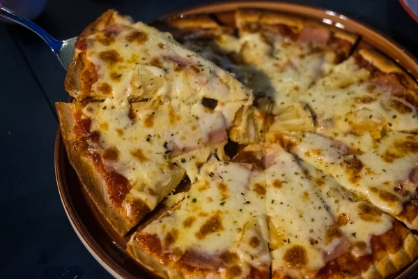 Man takes a slice of pizza melted cheese stretches on slice of hot pizza. Delicious Pizza, close up shot. Nutrition dinner or lunch