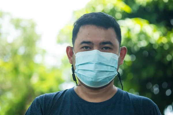 Portrait of Thai man wearing a mask on a nature blur background