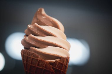 Hand holding a two tone chocolate and vanilla ice cream waffle. Close up