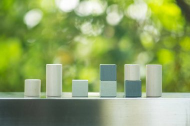 Wood cylinder blocks and square placed as like bar graph symbolizing sales growth on a nature background