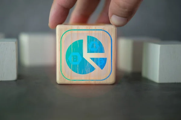 Hand putting wood block with icons of circle graph showing market share portion on wooden cube blocks, pie chart