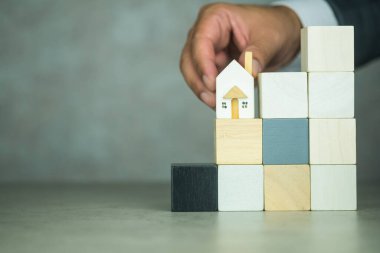 İşadamları ev modellerini boş tahta bloğun basamaklarına yerleştiriyor. Planlama ve yatırım gayrimenkul işi, bir konsept inşa etmek