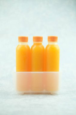 Kutusunda portakal suyu olan üç plastik şişe. Yakın plan.