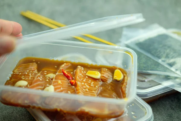 男人的手打开一盒鲜鲑鱼的盖子 韩式酱油腌制韩式食品 — 图库照片