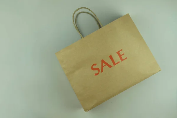 Brown paper carrier bag with handles for shopping with sale red text.