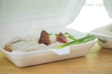Asian fresh spring rolls and spring onion, topped with crab meat, green chili in foam box.
