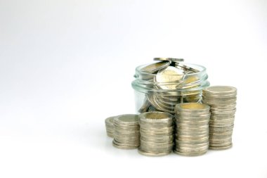 Beyaz arka planda cam kavanozdaki bozuk paralar. Sürdürülebilir adımları takip ederek finansal büyümeyi gösterir.