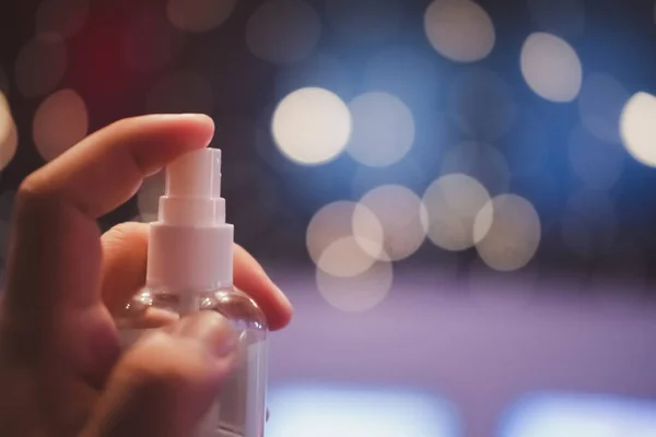 Close up of man sanitizing her hand with disinfectant spray against on bokeh background
