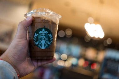 Samut Prakan, Tayland - 14 Ekim 2022 Starbucks kahve dükkanında elinde plastik bardak Starbucks kahvesi tutan adam. Kapat.