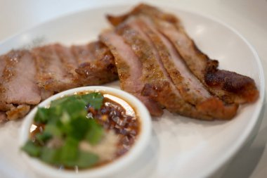Tayland baharatlı sosuyla servis edilmiş ızgara domuz eti. Kapat.