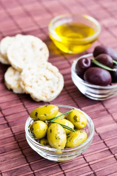 Green and black olives with rice cakes on bamboo napkin — Stock Photo, Image