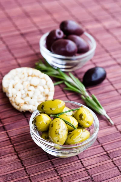 Green and black olives with rice cakes on bamboo napkin — Stock Photo, Image