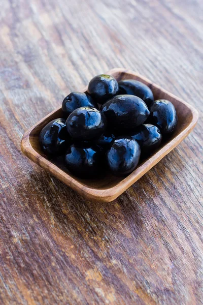 Plate of black olives on wooden surface — Stock Photo, Image