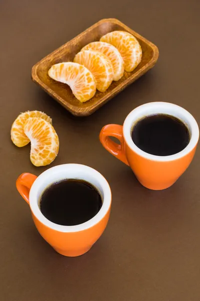 Duas xícaras de café em uma superfície marrom com fatias de mandarim — Fotografia de Stock