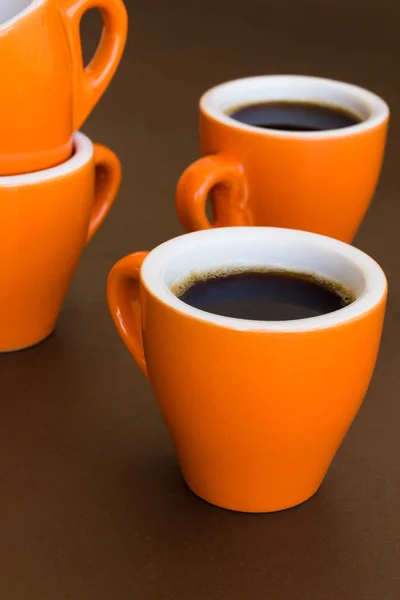 Four modern cups of coffee on a brown surface — Stock Photo, Image