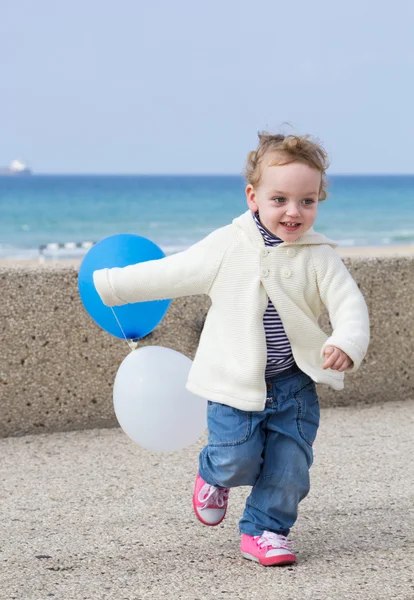 Adorable little girl playing on a winter beach — Stock Photo, Image