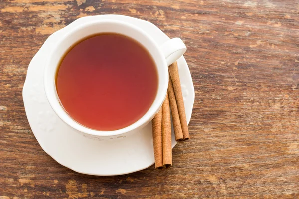 Taza de té con canela sobre una superficie de madera — Foto de Stock