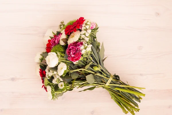 Strauß weißer, rosa und roter Blumen auf einer Holzoberfläche Stockfoto