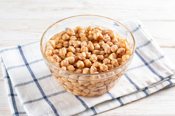 Chickpea soaked in water in a glass bowl on wooden table. Ingredients for cooking