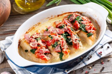 Ana yemek olarak kurutulmuş domatesli tavuk ve ahşap masadaki tavaya yakın plan peynir soslu ıspanak. Yatay