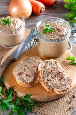 Ekmeğin üzerinde tavuk ciğeri ezmesi ve kırsal ahşap arka planda bir kavanozda