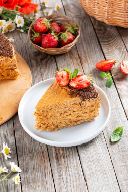 Tahta bir masanın üzerinde yoğunlaştırılmış süt, çikolata ve çilekli iştah açıcı waffle keki.