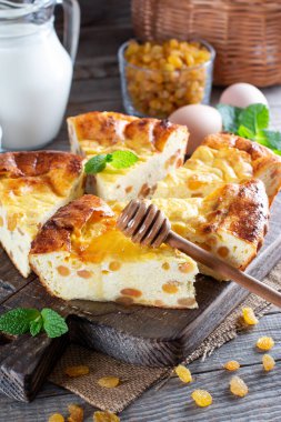 Kuru üzümlü ev yapımı süzme peynir güveci kesim tahtasının üzerinde naneli yapraklar.