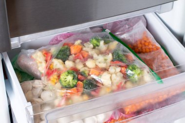 Buzdolabında farklı donmuş sebzeler olan plastik poşetler. Yiyecek deposu