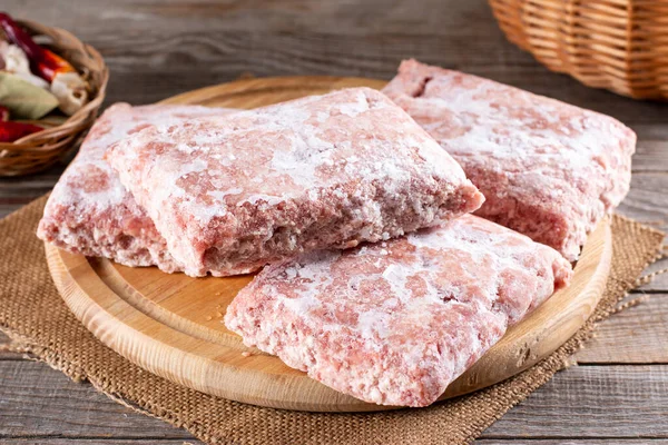 Frozen ground meat, minced pork on a wooden board. Ground chicken inclusive backs, necks, liver and heart. Frozen food. Concept for raw food diet for cats, dogs and pets. Food storage