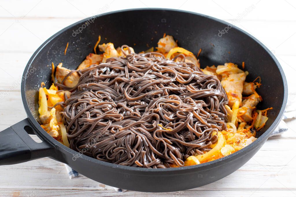 Buckwheat soba noodles in a frying pan. Preparation Japanese dish buckwheat noodles with vegetables and meat. Step by step, recipe