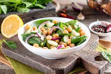 Bir tabakta nohut, ıspanak, salatalık, soğan ve yeşillik salatası. Beslenme yemeği. Vegan salatası.