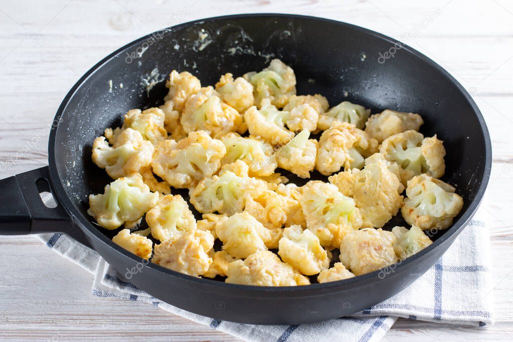 Steaming roasted cauliflower florets in a frying pan, cooking vegetables for a healthy vegetarian dish, selected focus, narrow depth of field