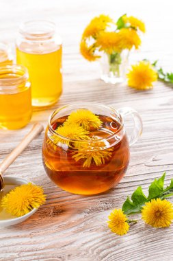 Cam bardakta karahindiba ve ahşap masada ballı karahindiba çayı.