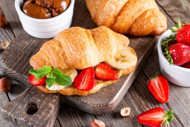 Tahta masada taze kruvasan, çikolata, muz ve çilekli nefis bir kahvaltı. Fransız pastası.