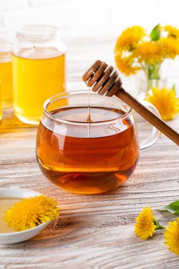 Cam bardakta karahindiba ve ahşap masada ballı karahindiba çayı.