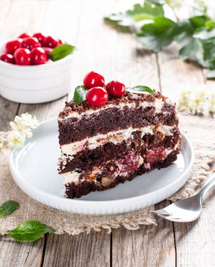 Tahta bir masada kırmızı kirazlı siyah çikolatalı kek.