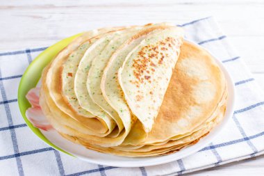 Beyaz tabakta taze dereotlu ve soğanlı krep yığını. Maslenitsa için geleneksel Rus krepleri.