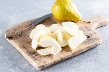 Masadaki kesme tahtasının üzerinde taze armut dilimlenmiş.