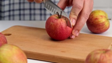 Erkek eller, tahta tahtayı bıçakla keserek kırmızı elmayı parçalara ayırıyor. Kapat..