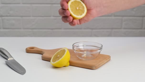 在一个木制切菜板上的玻璃碟上切半个柠檬 — 图库视频影像