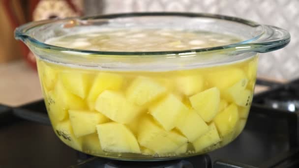 在煤气炉上的玻璃锅中 用生土豆在低温下沸腾的水 — 图库视频影像