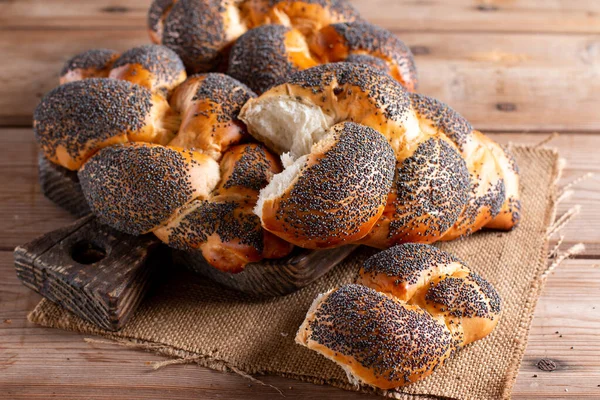 Haşhaş tohumlu taze ev yapımı çörekler. Ahşap arka planda ev yapımı ekmek, yakın plan.