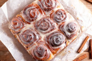 Tarçınlı ve kremalı ev yapımı tarçınlı çörekler. Ahşap arka plan. Seçici odak